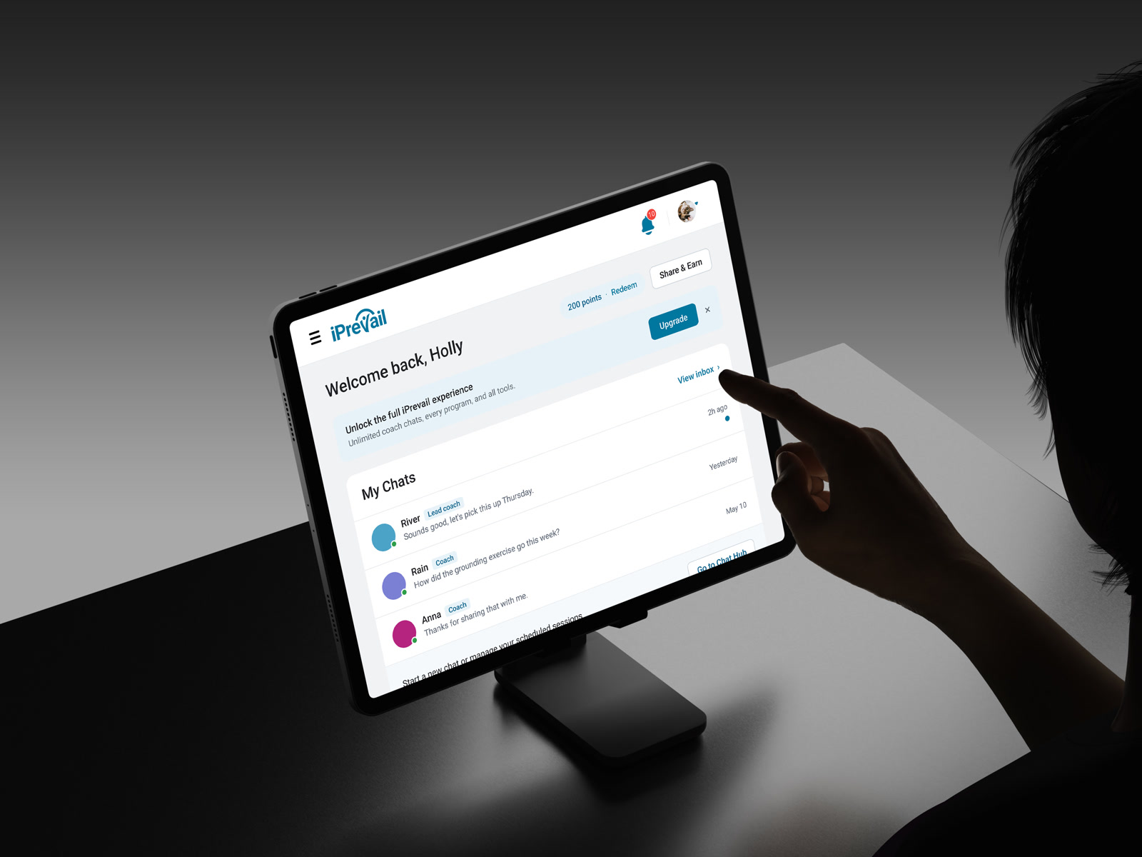 A hand reaching for the chat-priority dashboard on a tablet, coach conversations in view